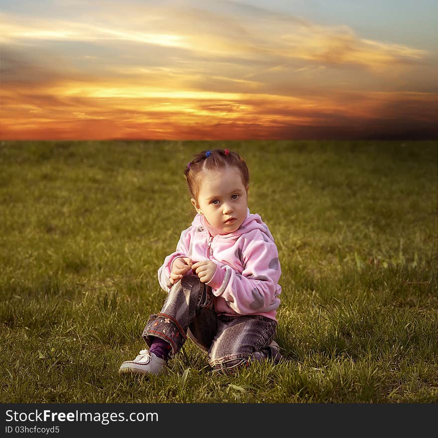 The child playing a ball on the meadow filled in with the sun