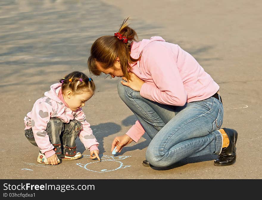 The child with mum draw a chalk