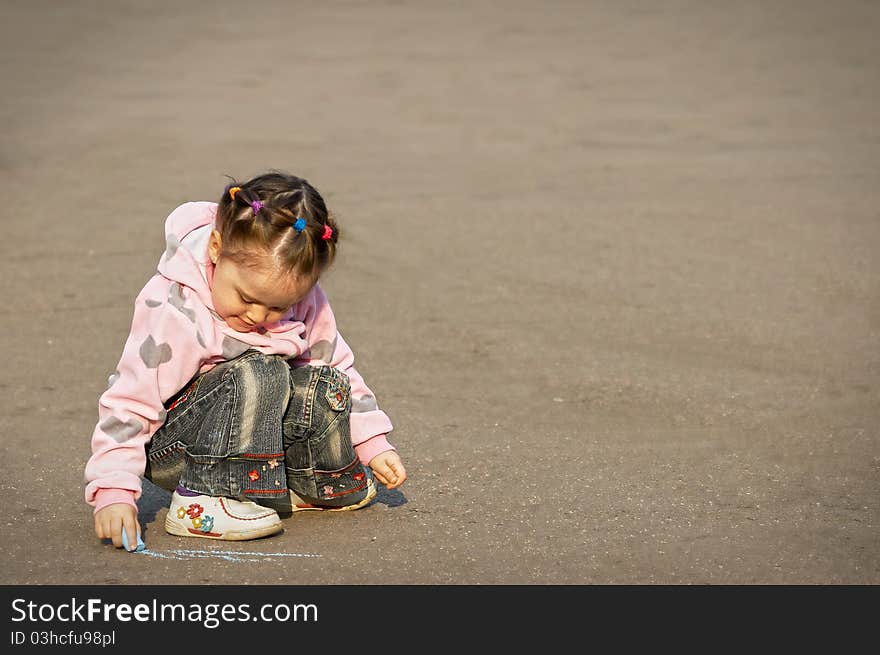 The child drawing a chalk on asphalt.outdoor