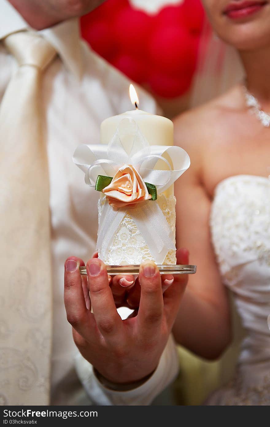 Candle in hands of newlyweds