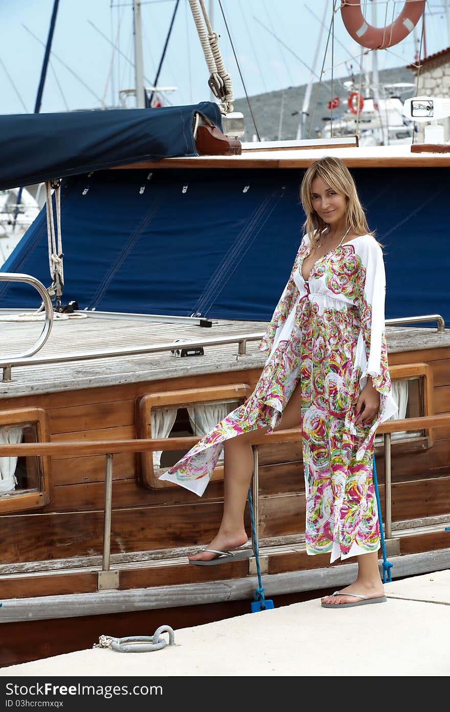 Sexy blond woman posing in front of the boats at the marina