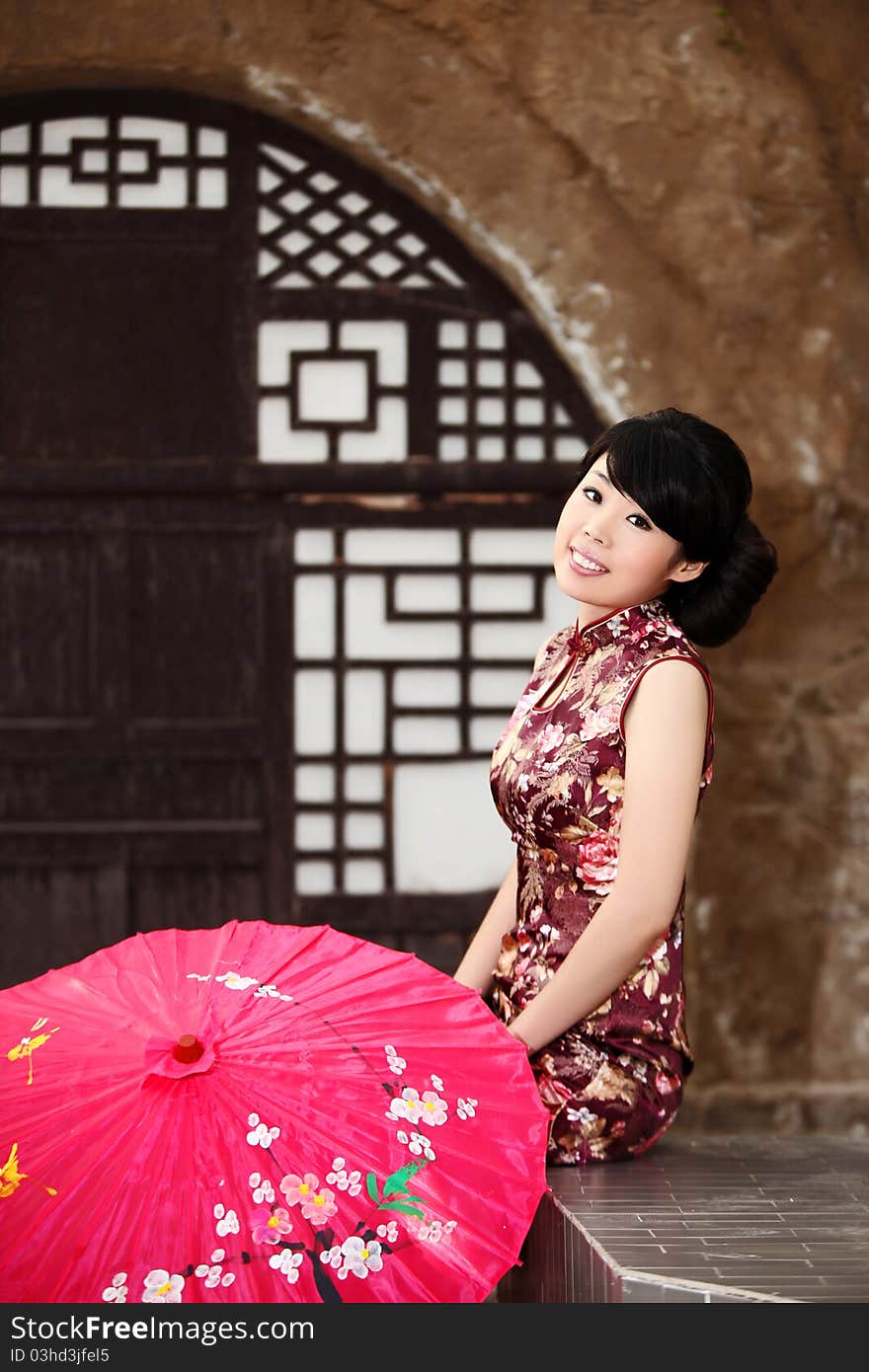 A pretty Chinese girl in cheongsam sitting outside the loess cave residence. A pretty Chinese girl in cheongsam sitting outside the loess cave residence.