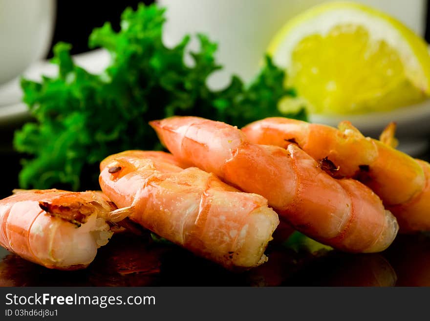 Photo of grilled king prawns on black glass table with reflection. Photo of grilled king prawns on black glass table with reflection