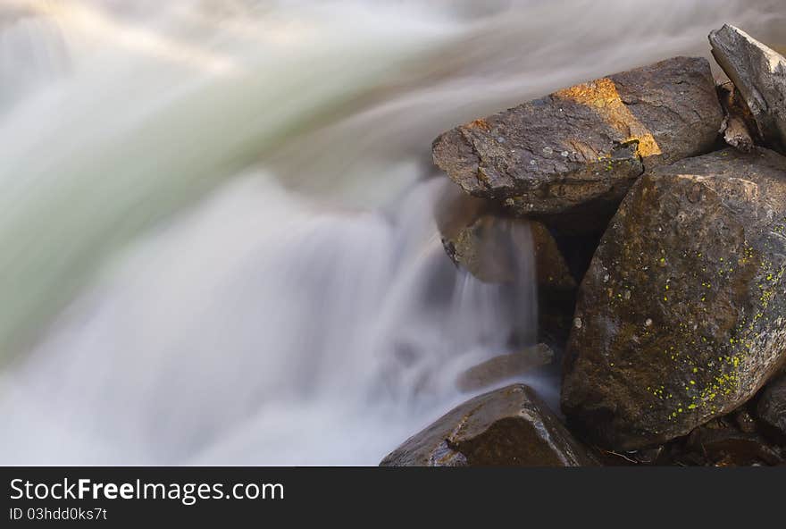 Fast flowing motion blurred water over river rocks. Fast flowing motion blurred water over river rocks