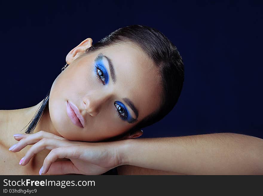 Beautiful girl with blue make-up in long earrings