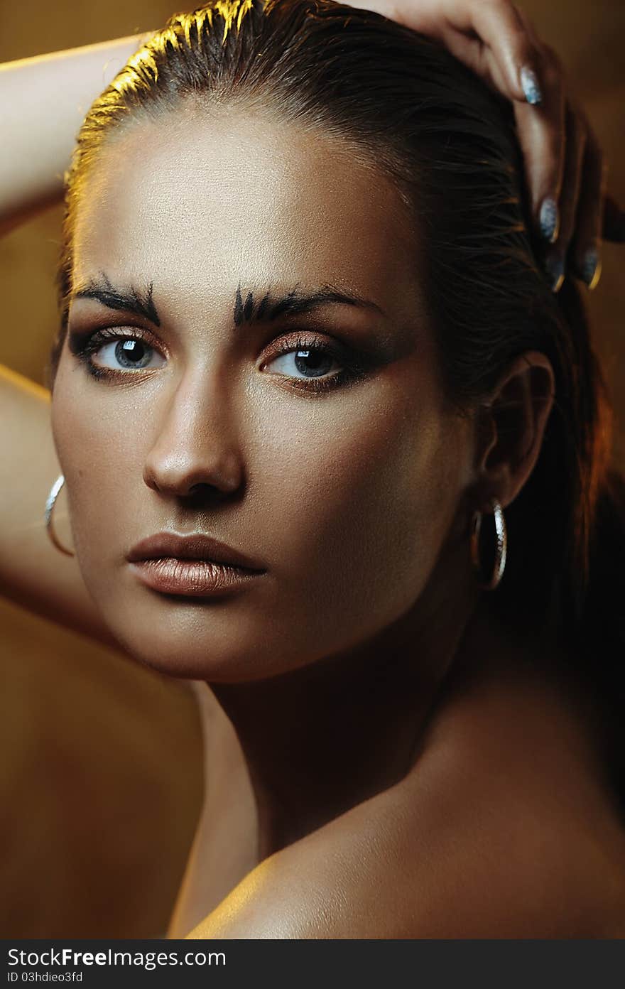 Beautiful young woman with gold makeup and with drops of water on her face