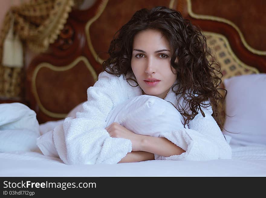 Beautiful woman lying on a bed in a white bathrobe