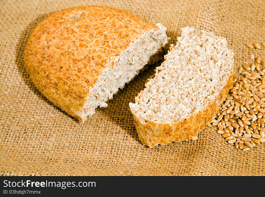 The loaf of bread lying together with wheat on a linen cloth. The loaf of bread lying together with wheat on a linen cloth