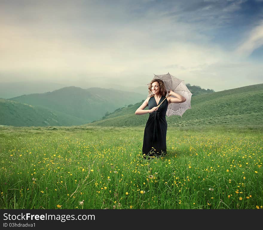 Beautiful woman holding an umbrella on a green meadow. Beautiful woman holding an umbrella on a green meadow