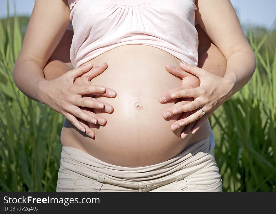 Hands covering pregnant belly - bonding. Hands covering pregnant belly - bonding