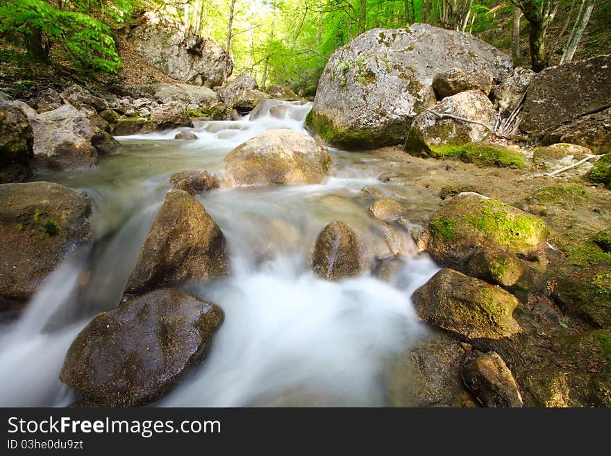 The mountain river in gorge with a spring