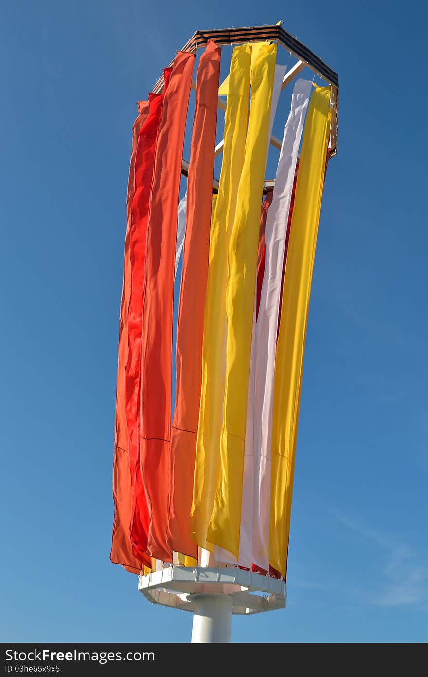 Strong wind and varicolored flags on a blue sky background