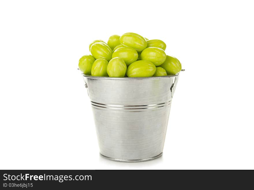 Many green candies in a steel bucket. Isolated on white background. Many green candies in a steel bucket. Isolated on white background