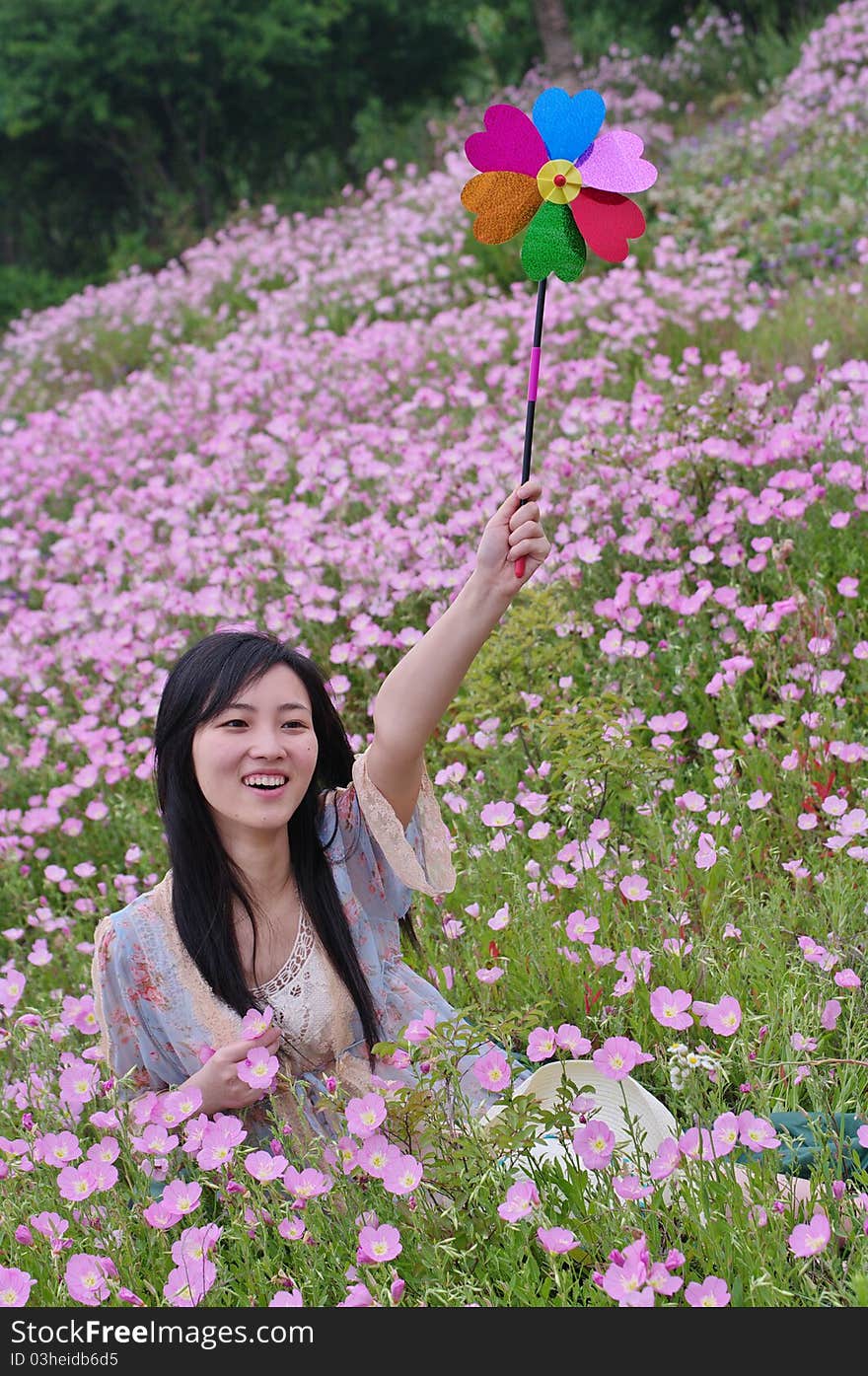 A girl in field with pinwheel in hand and flowers around