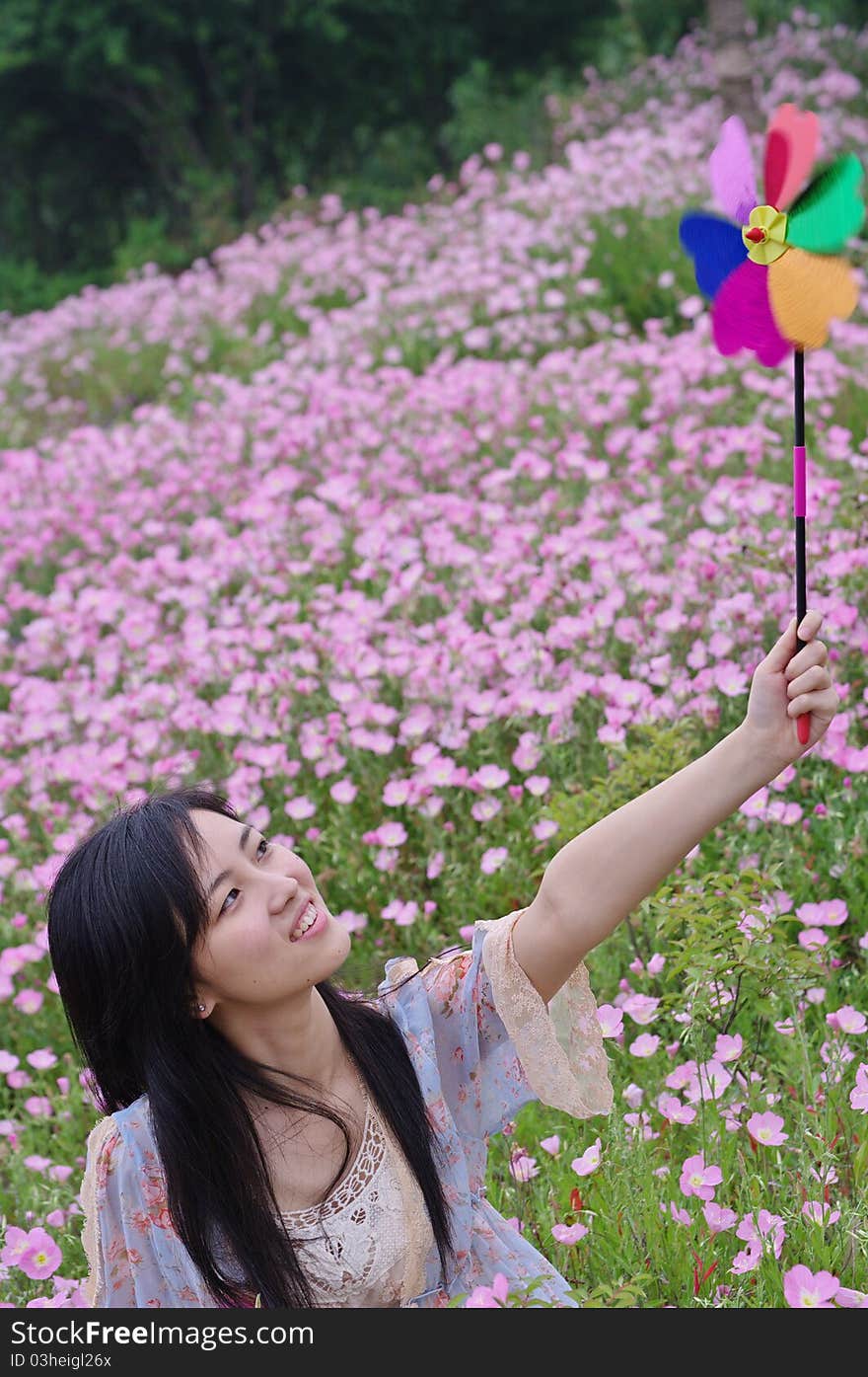 A girl in field with pinwheel in hand and flowers around