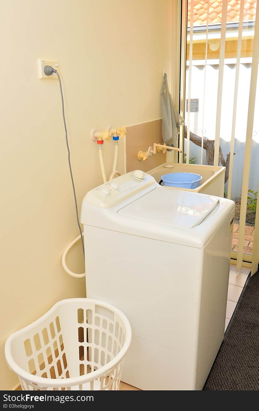 Interior of washing area with white washing machine and laundry basket.