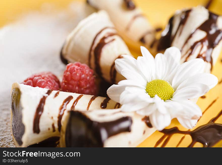 Piece of cake on plate with berries and fruits and camomile