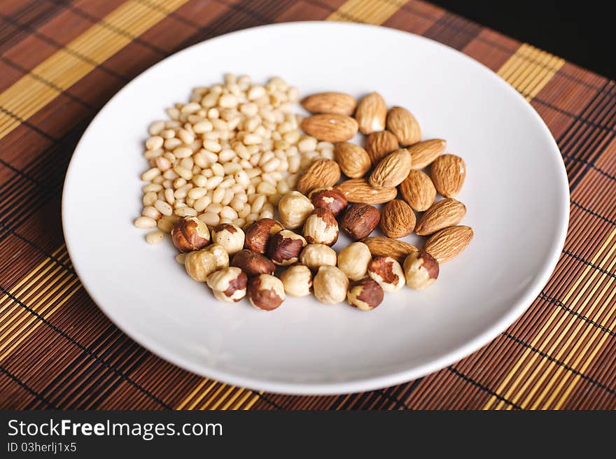 Mixed nuts on a white plate and brown table-napkin