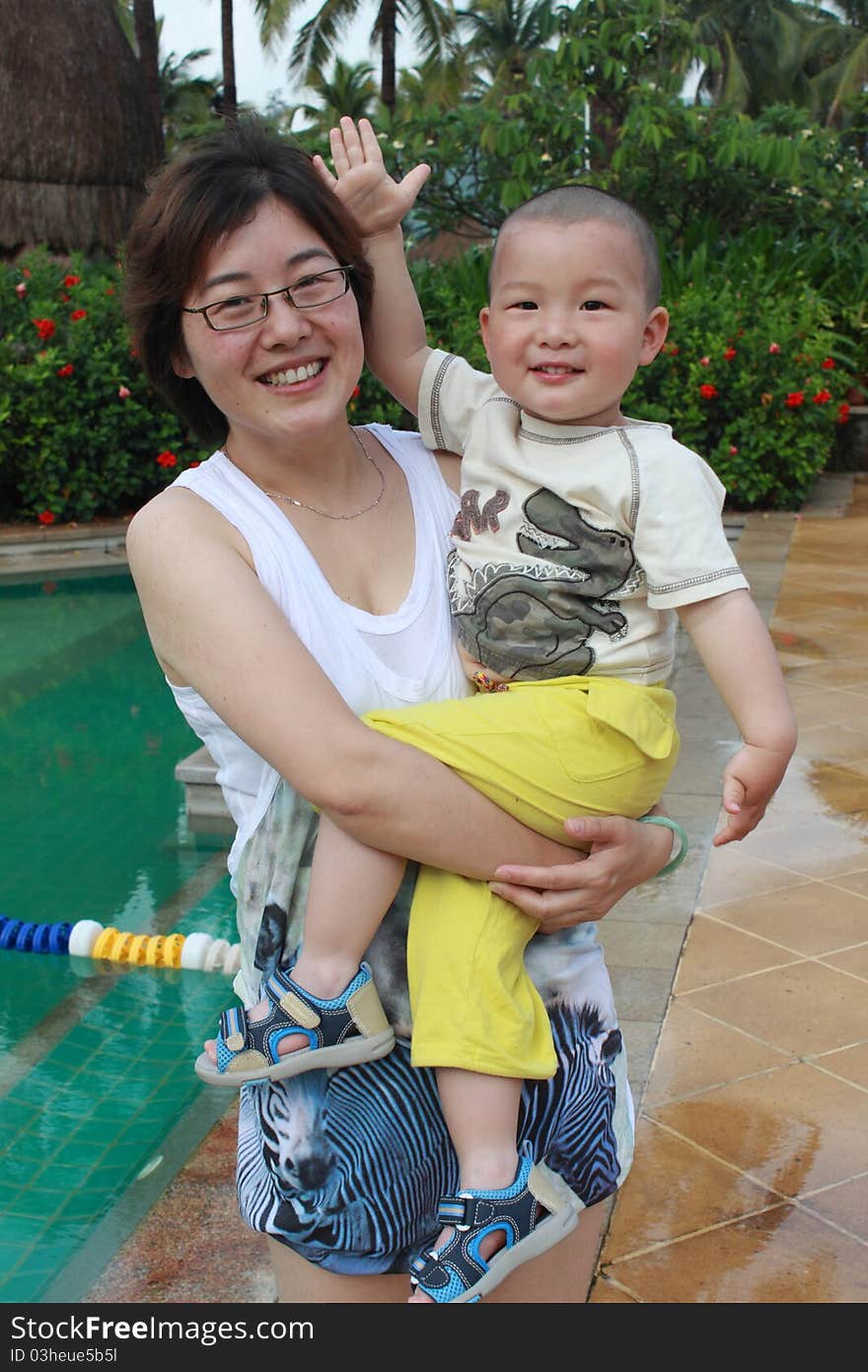 Young chinese mother with cute baby by the swimming pool. Young chinese mother with cute baby by the swimming pool