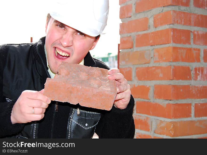 Young bricklayer in the helmet with brick. Young bricklayer in the helmet with brick.