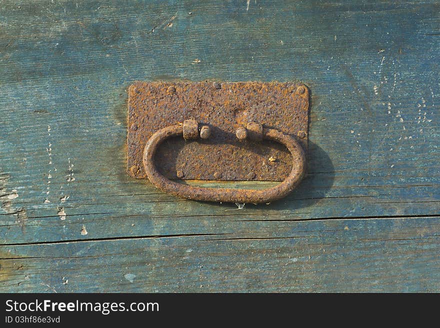 Close-up of rusty vintage handle on blue board. Close-up of rusty vintage handle on blue board