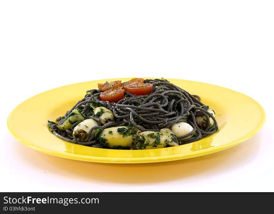 A yellow plate with black pasta and squid