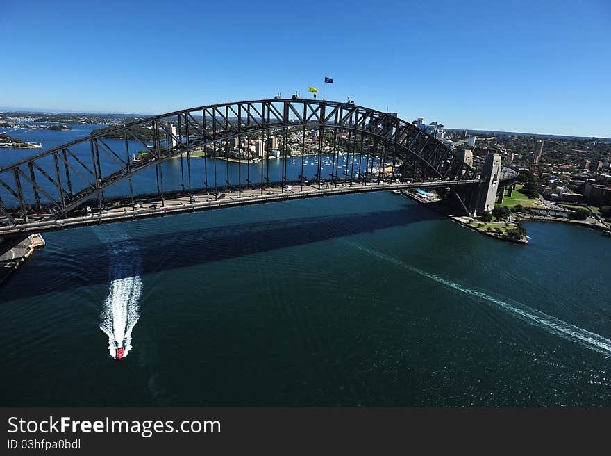 An aerial view of the Sydney Harbour Bridge as the sunlight shimmers on the water below.