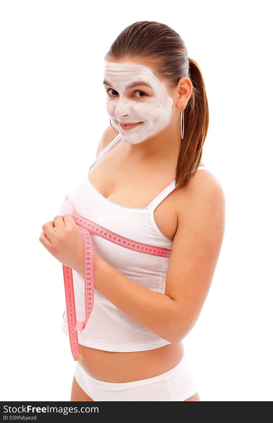 Young woman with a beauty mask measures her breast with a measuring tape. Young woman with a beauty mask measures her breast with a measuring tape