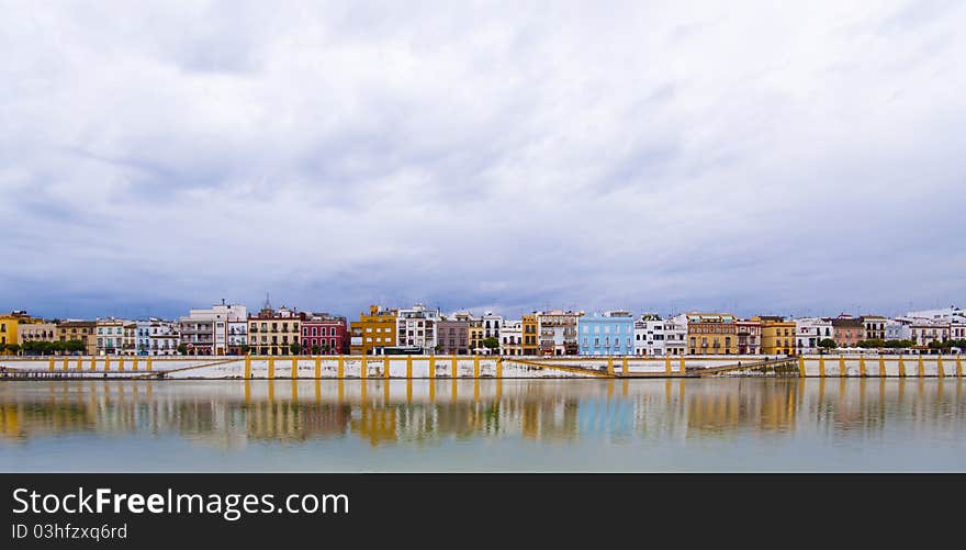 Colorful panorama of Seville riverside on the overcast day, forming amazing pastel colors and reflections in the river. Colorful panorama of Seville riverside on the overcast day, forming amazing pastel colors and reflections in the river.