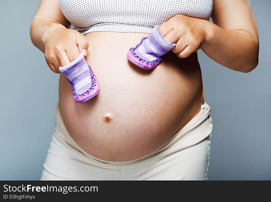 Pregnant woman holding pair of shoes for baby