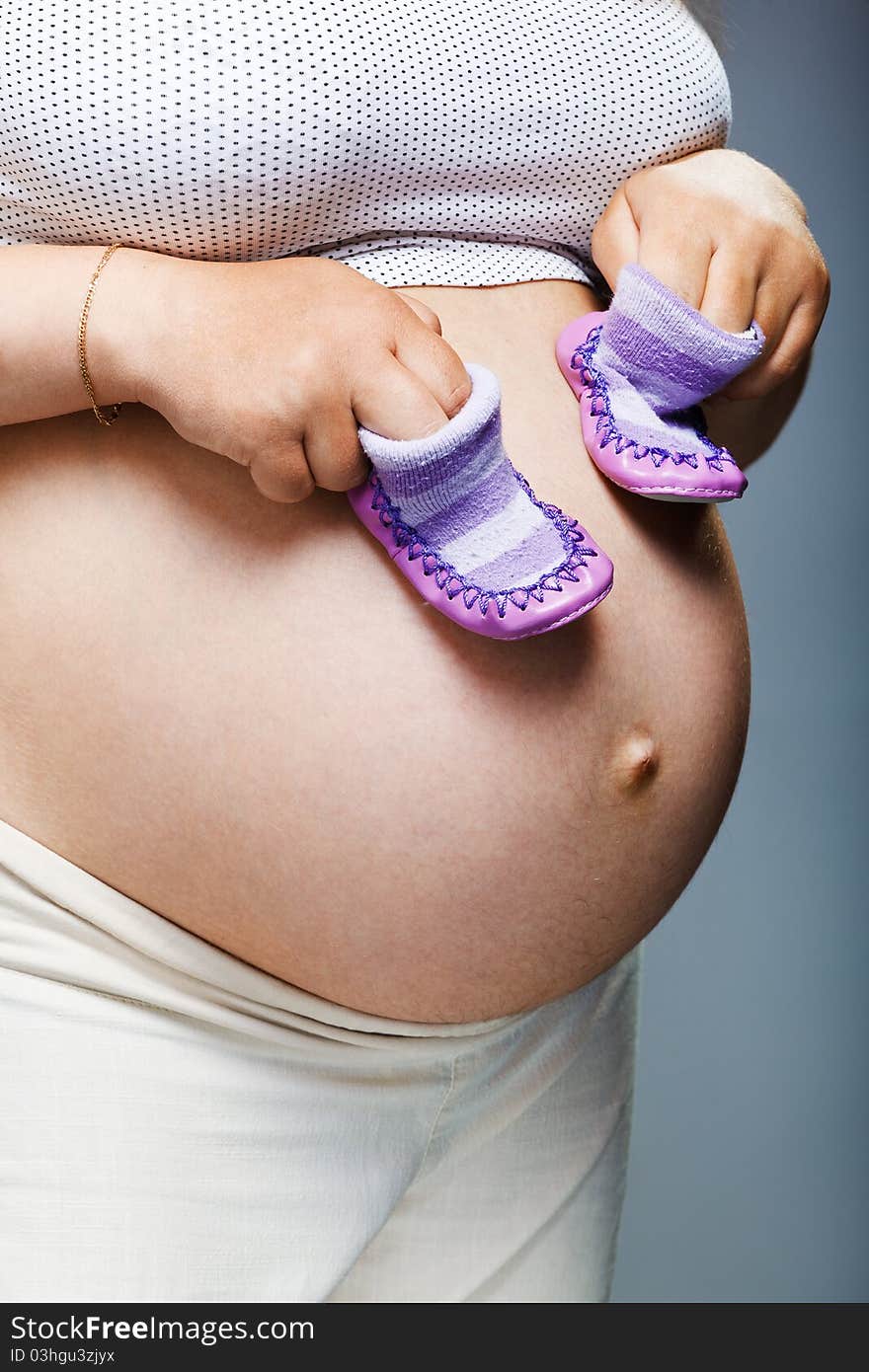 Pregnant woman holding pair of shoes