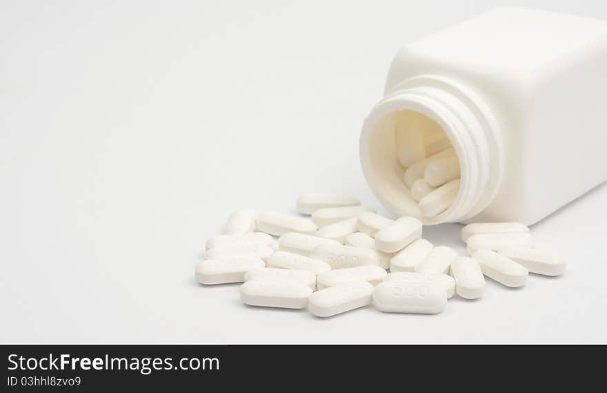 Pills scattered from vials against white background