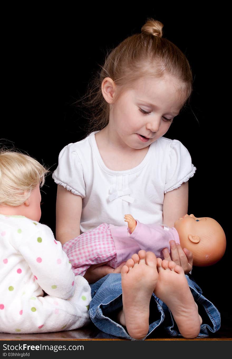 A young child plays with her dolls. She is having too much fun!. A young child plays with her dolls. She is having too much fun!