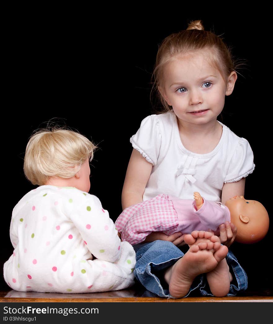 A young child plays with her dolls. She is having too much fun!. A young child plays with her dolls. She is having too much fun!