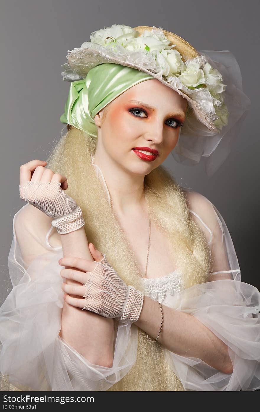 Fashion portrait of a woman in hat made of flowers