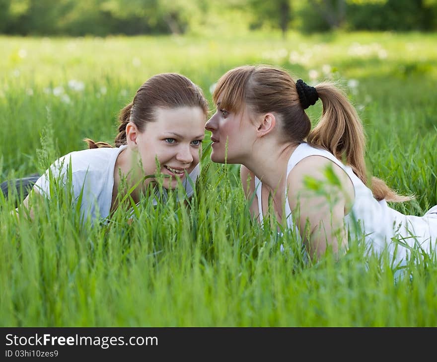 Girls lying in a grass and telling secret to each other. Girls lying in a grass and telling secret to each other