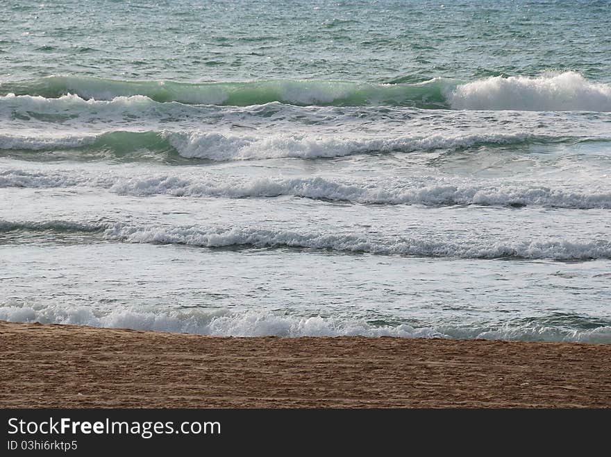 Sea coast with small waves and white foam