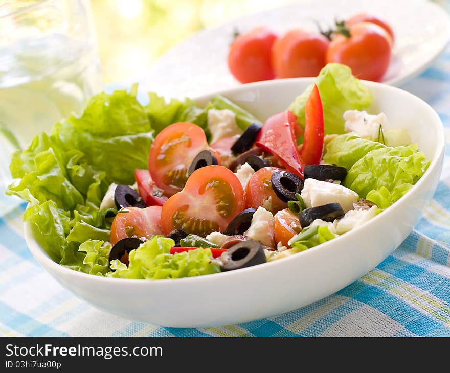 Fresh salad from raw vegetables, lettuce and olive. Selective focus