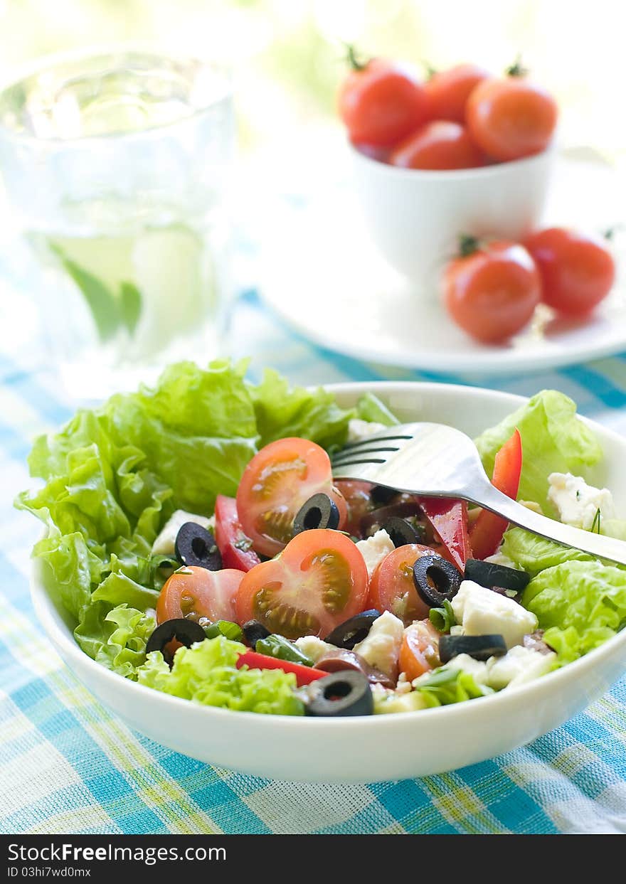 Fresh salad from raw vegetables, lettuce and olive. Selective focus