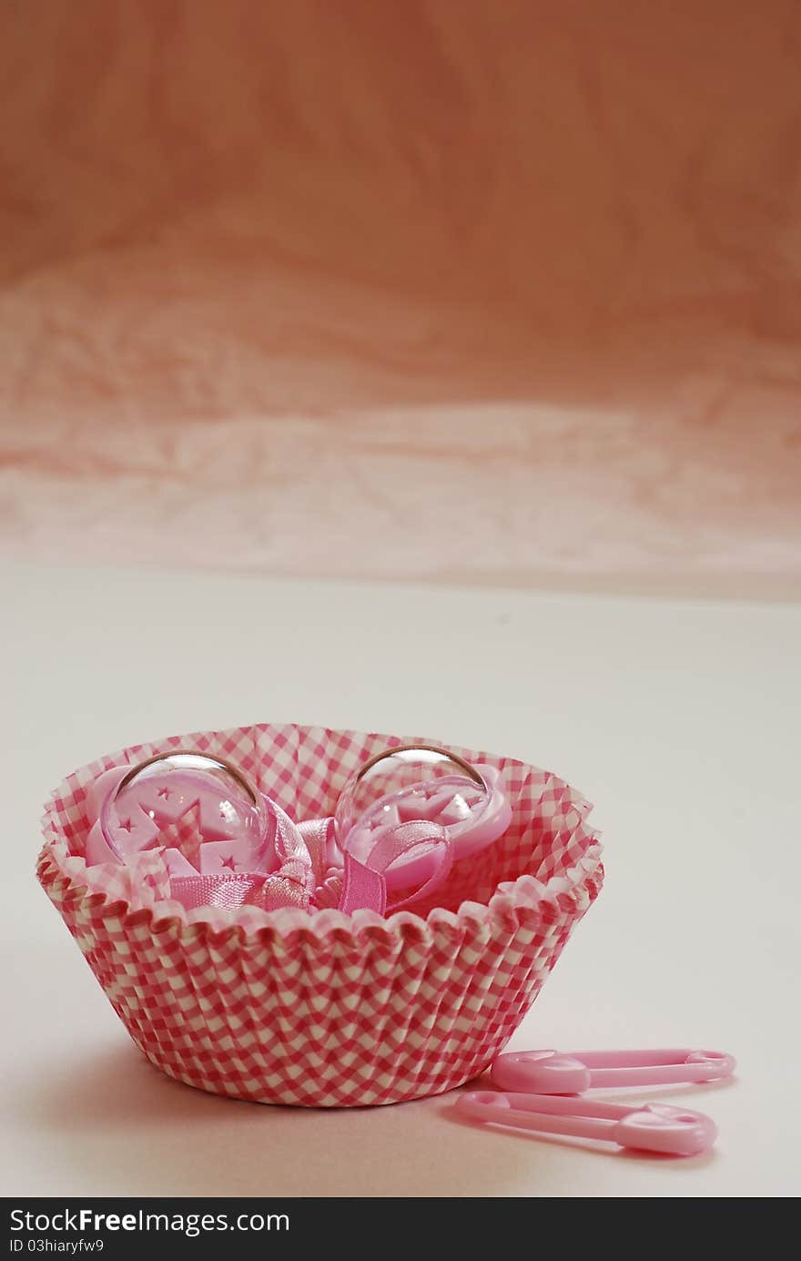 Pink baby rattles in white and red paper cup cake holders. Pink baby rattles in white and red paper cup cake holders