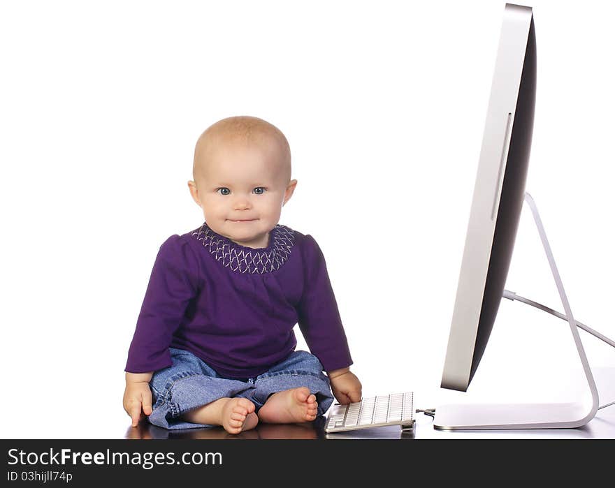 Infant baby girl sitting up looking playing with a desktop computer screen and keyboard. Infant baby girl sitting up looking playing with a desktop computer screen and keyboard.