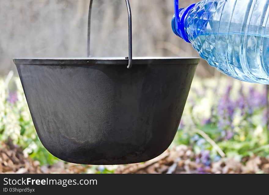 In a pot pour the water for cooking on the campfire. In a pot pour the water for cooking on the campfire.