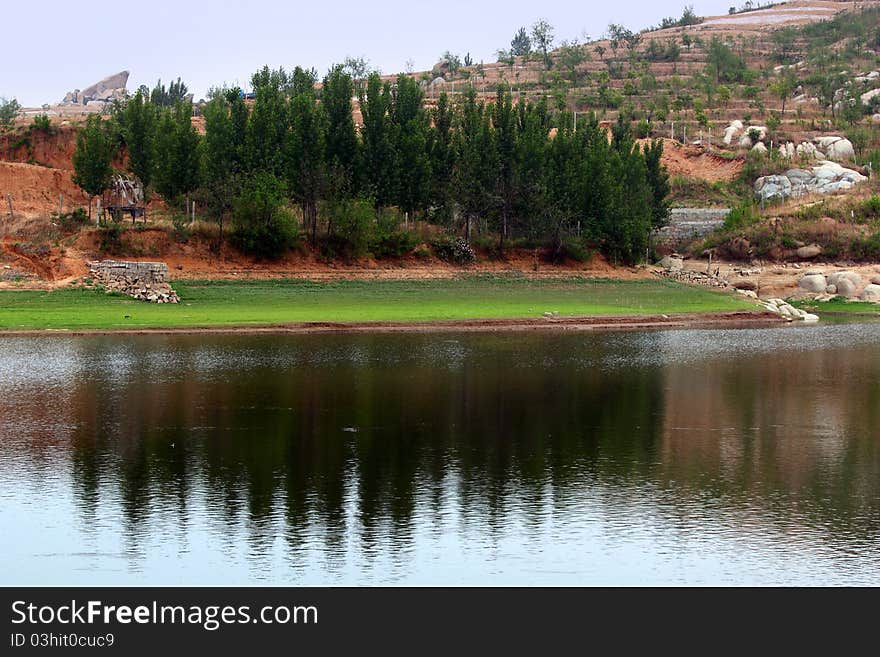 Lakeside with hill and calm lake.