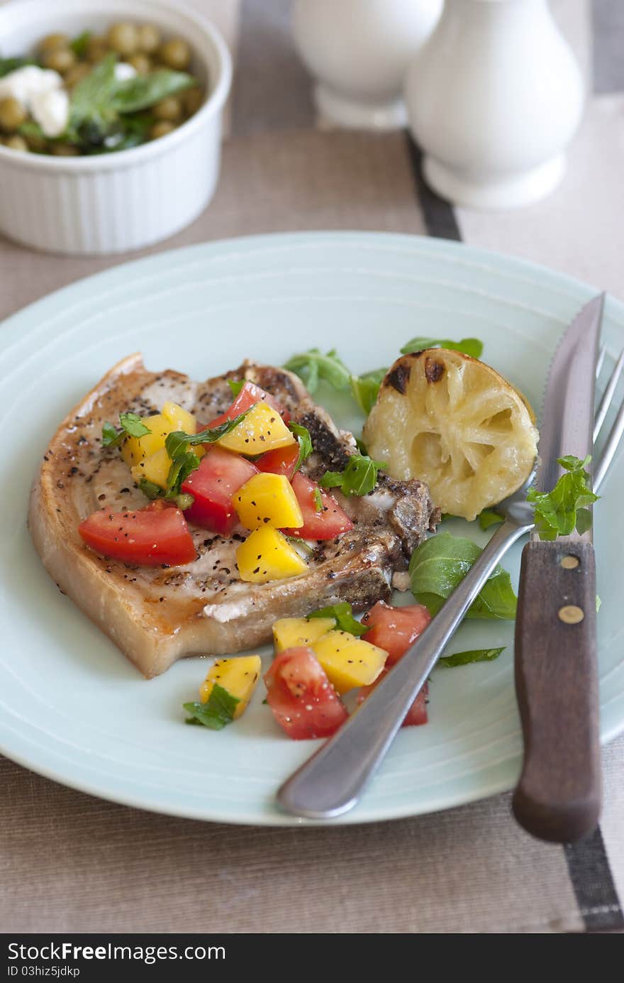 Southern-style pork chop with mango and tomatoes