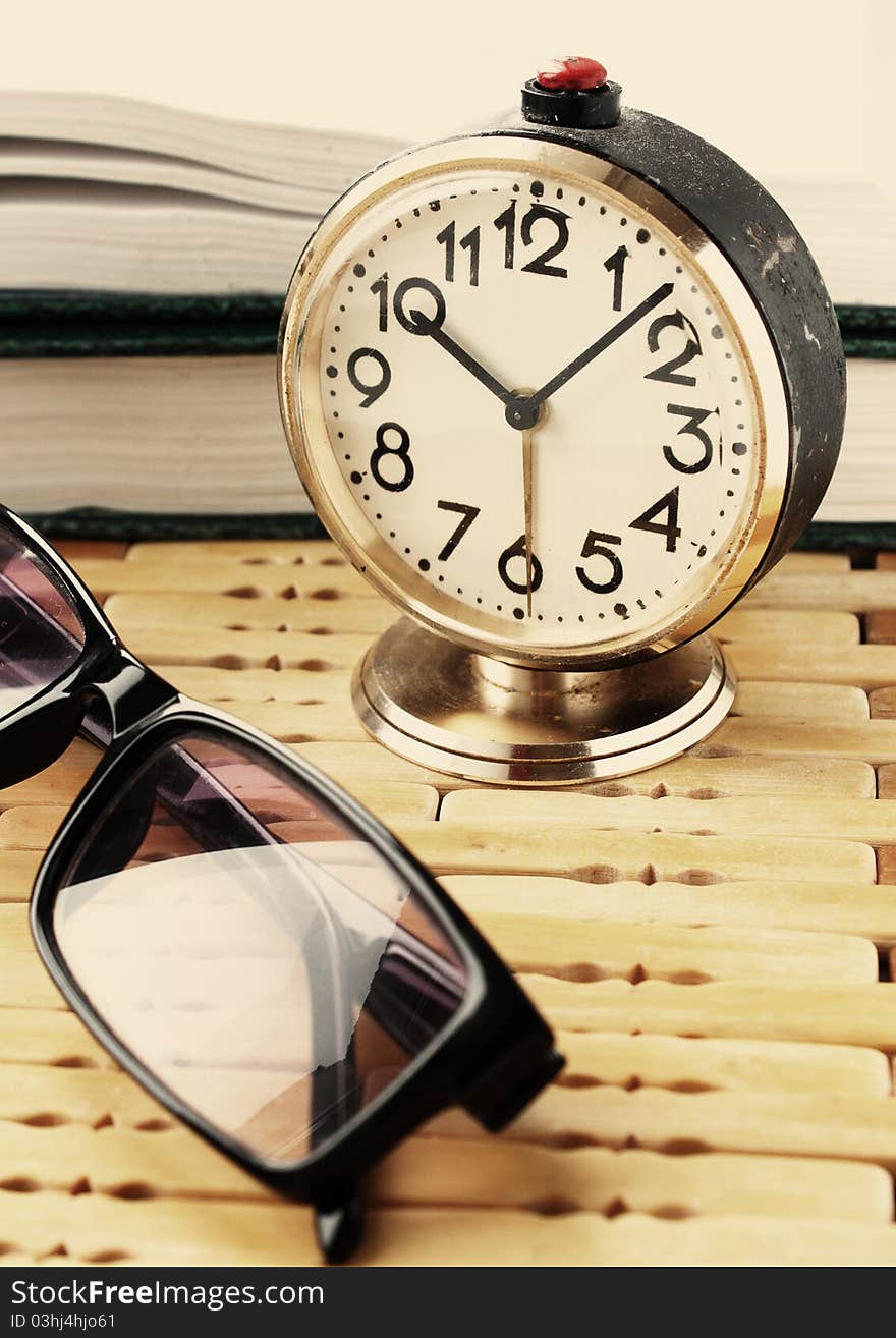 Book with alarm clock and eyeglasses. Book with alarm clock and eyeglasses