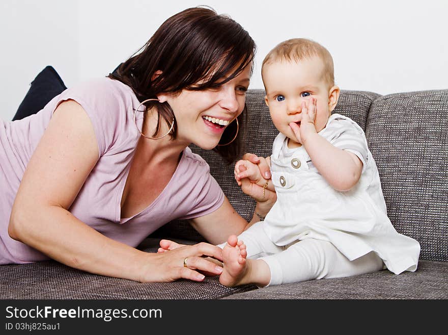 Young baby girl with cute dress and mother playing on the couch. Young baby girl with cute dress and mother playing on the couch.