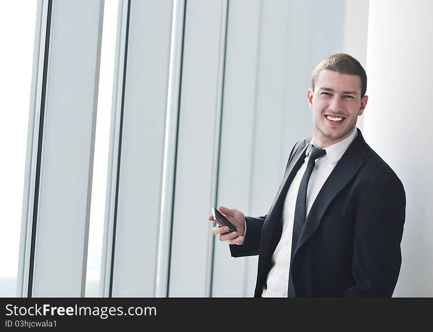 Young business man talk by cellphone over bright window in big hall