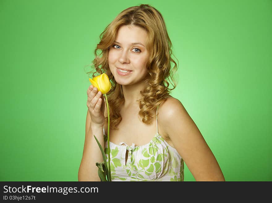 HappyClose up on a green background Happy young woman hugging a yellow tulip. Young Woman Hugging Flower. HappyClose up on a green background Happy young woman hugging a yellow tulip. Young Woman Hugging Flower