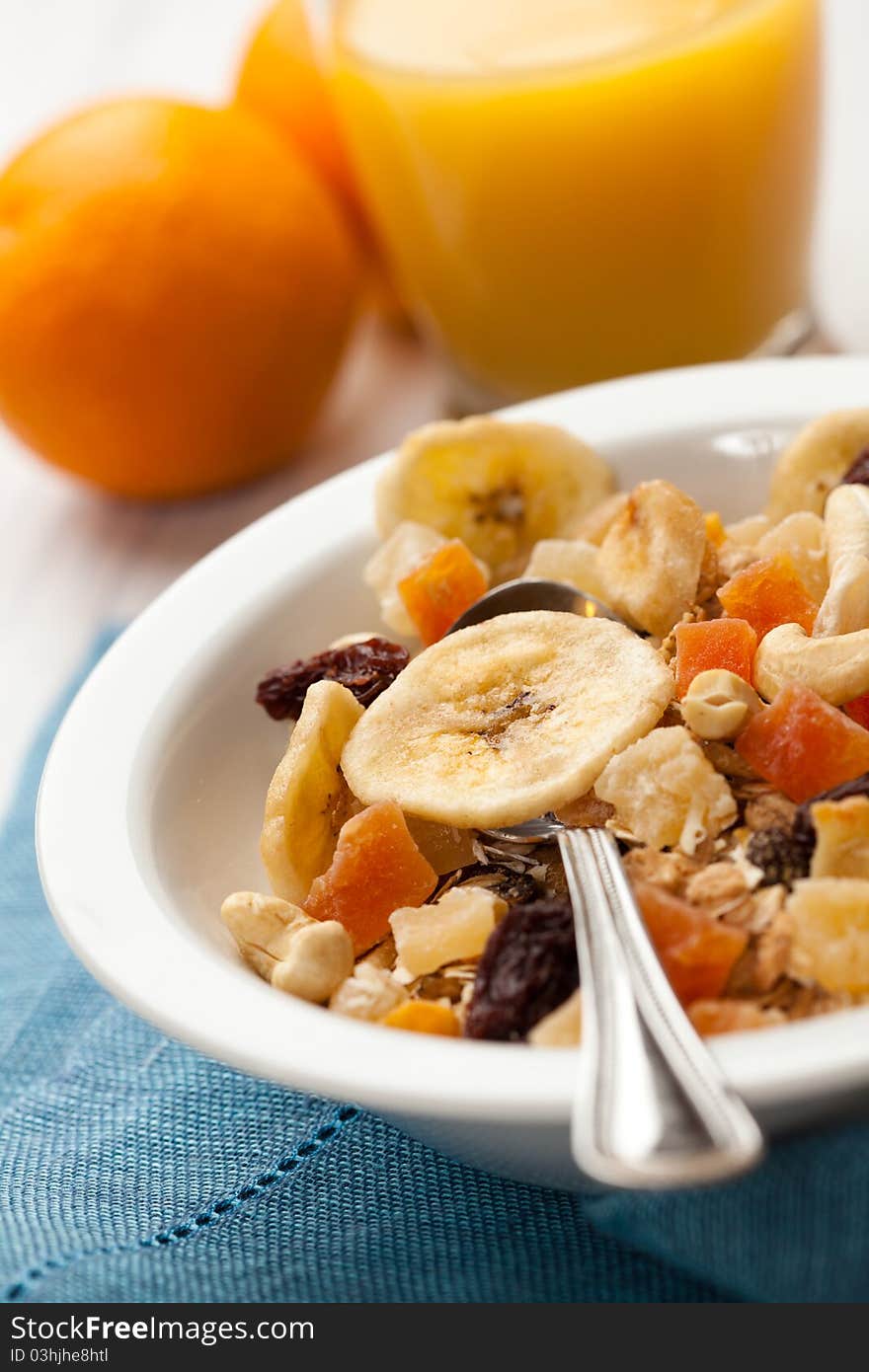 Bowl of muesli and orange juice in background