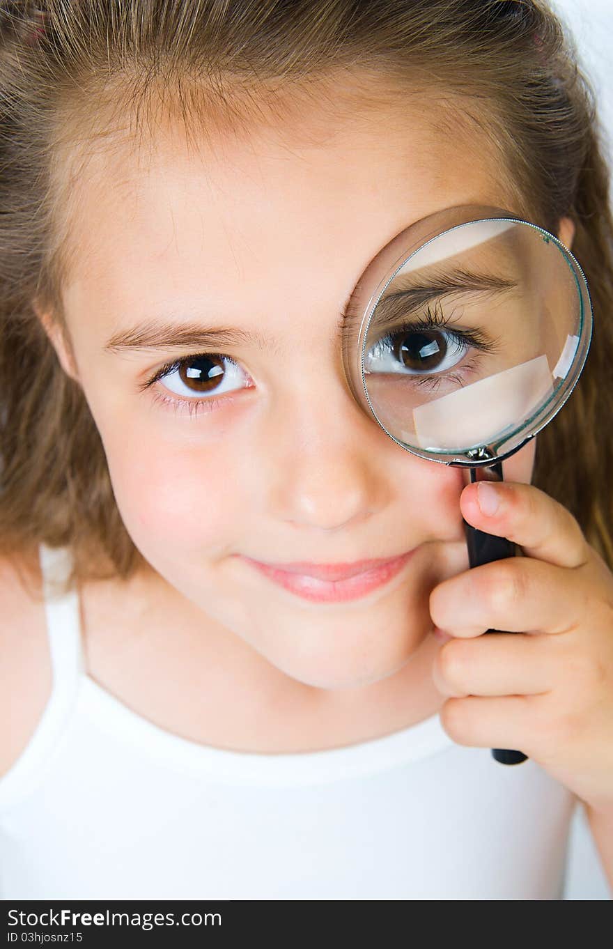 Beautiful little girl looking through a magnifying glass